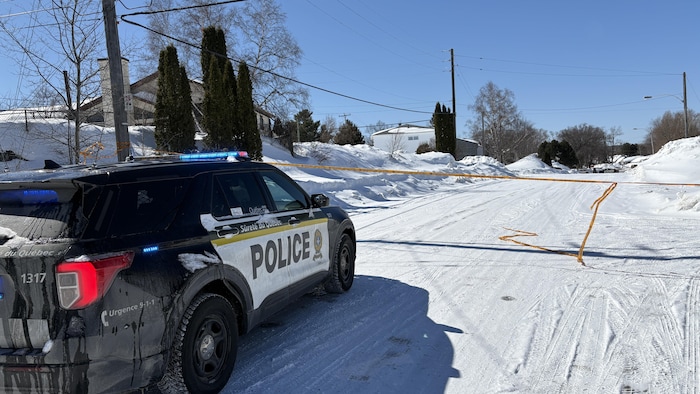 Un véhicule de la Sûreté du Québec arrêté au milieu d'une rue pour une intervention. 