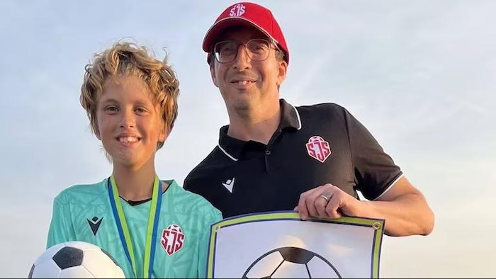 Un jeune tenant un ballon de soccer et un adulte tenant ce qui ressemble à une pancarte.