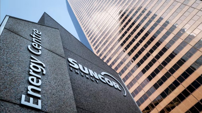 Vue rapprochée et en contre-plongée de l'entrée du Suncor Energy Centre à Calgary, montrant l'inscription en relief « SUNCOR ENERGY » sur un mur en béton sombre.