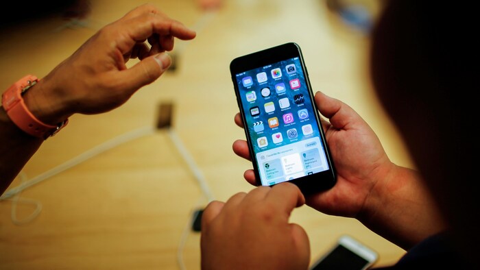 Plan rapproché des mains d'une personne manipulant un iPhone 7.