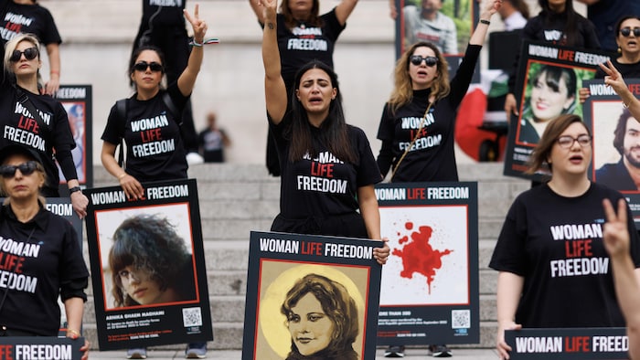 Des femmes portent des pancartes avec les portraits des femmes tuées lors du  soulèvement populaire qui a secoué l'Iran l'année dernière. Elles portent des chandails sur lesquels sont inscrits les mots «Femme, vie, liberté». 