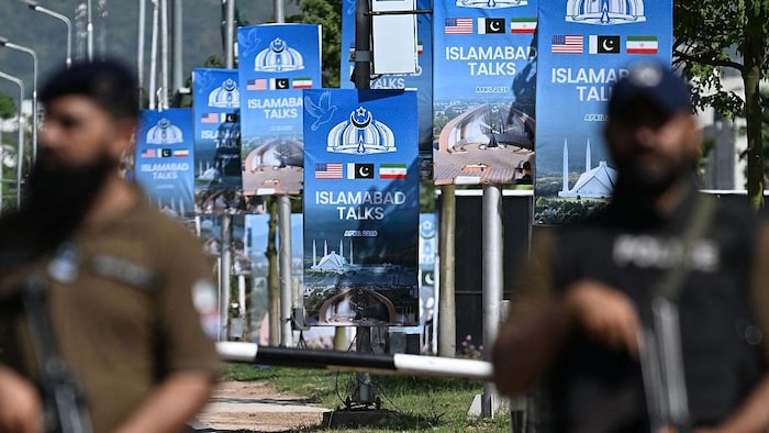 Des soldats armés de mitraillettes dans une rue bordée de banderoles évoquant les pourparlers irano-américains
