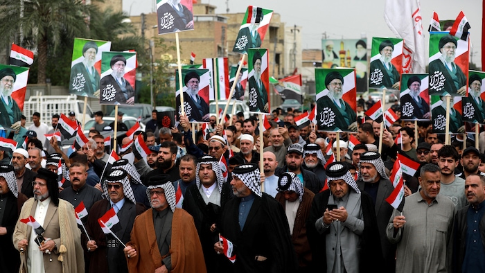 Des Irakiens brandissent des drapeaux de l'Irak et des portraits d'Ali Khamenei.
