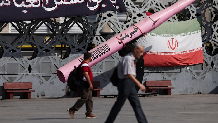 Des gens passent à côté d'une maquette symbolique d'un missile iranien et d'un drapeau iranien.