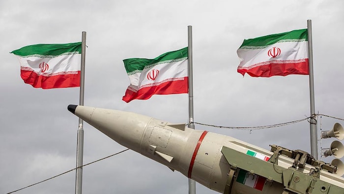 Un missile devant trois drapeaux de l'Iran volant au vent à Téhéran, le 11 février 2026.