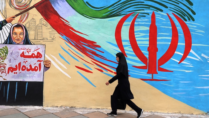 Une femme passe devant une murale à Téhéran.