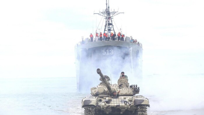 A tank of assault before a military ship. conflict israel-iran: strait ormuz, strategic