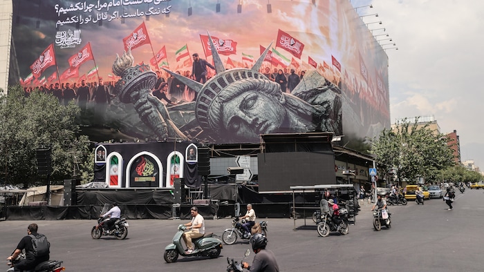 Des Iraniens passent devant un panneau d'affichage anti-États-Unis dans le centre de Téhéran, le 3 août 2026.