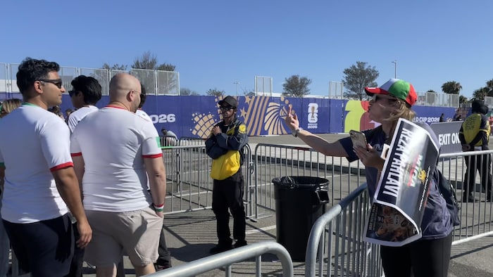 Une partisane du shah fait un doigt d'honneur à un groupe de supporters de l'équipe iranienne de soccer qui portent un maillot blanc.