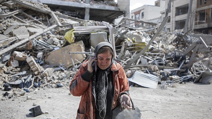 Une femme pleure devant un immeuble résidentiel réduit en ruine après une frappe aérienne dans l'ouest de Téhéran, le 30 mars 2026.