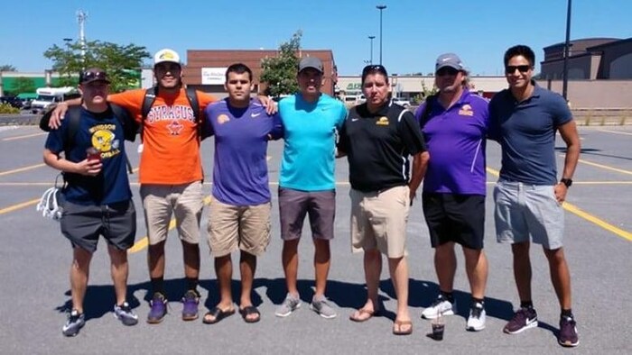 Des joueurs mohakws des Iroquois Nationals et leurs entraîneurs posent dans un stationnement avant leur départ.