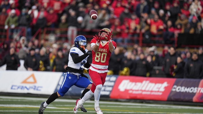 Il attrape un ballon avec un joueur des Carabins derrière lui.