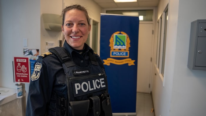 Une policière en uniforme est debout et sourit devant l’objectif.