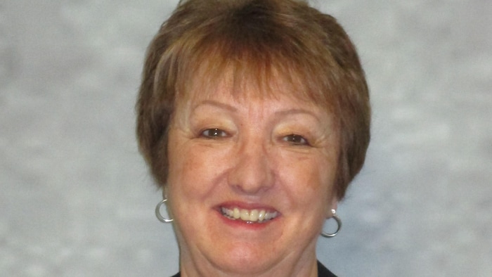 Une femme, Isabelle Charbonneau, présidente du conseil d’administration du Réseau du mieux-être francophone du Nord de l’Ontario, en veston noir.