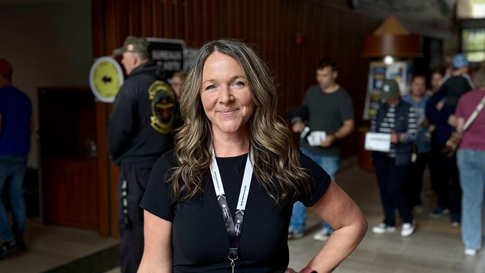 Isabelle Fleury sourit pour la photo devant une file d'électeurs.