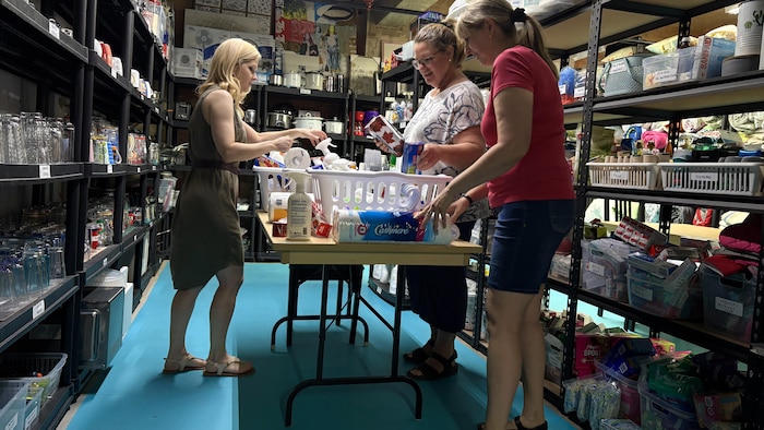 Trois femmes préparent des paniers de dons.