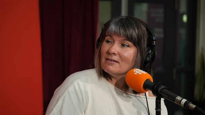 Isabelle Morin est derrière un micro de Radio-Canada lors d'une émission spéciale de l'émission Première heure, le 4 septembre 2026, au cégep Limoilou. Elle porte un casque d'écoute sur la tête.