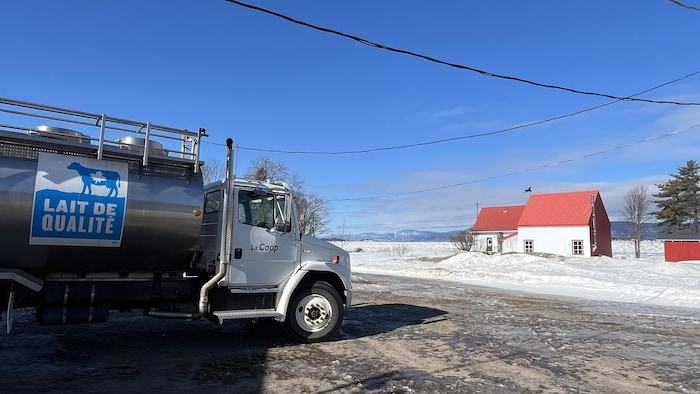 Un camion transportant du lait devant une maison ancestrale.
