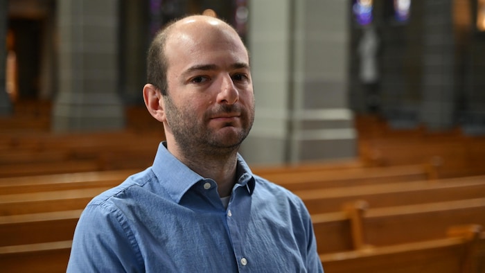 Ismet Baba-Moussa pose pour la photo à l'intérieur de la cathédrale. 