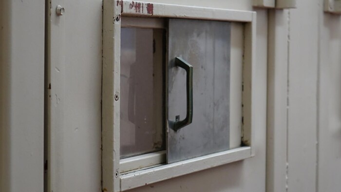 Photo d'une petite fenêtre dans une porte de prison.