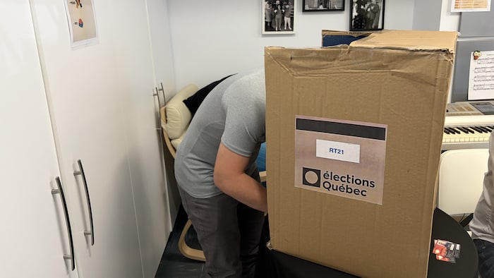 Une personne derrière un isoloir en carton.
