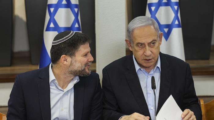 Bezalel Smotrich sourit tout en parlant à Benyamin Nétanyahou qui l'écoute, pensif.