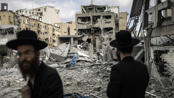 Deux hommes regardent un immeuble détruit.
