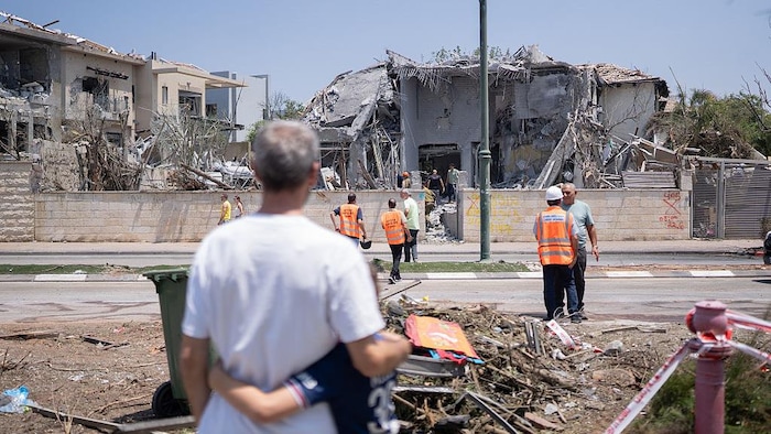 A man and a child look at the damage of a strike in Israel.