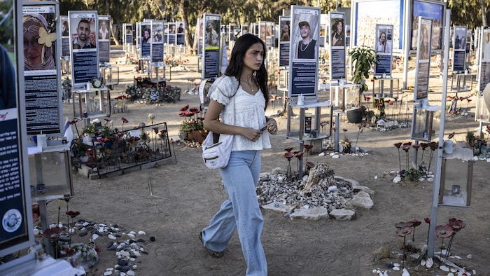 Une femme se promène parmi des pancartes portant les photos des victimes.