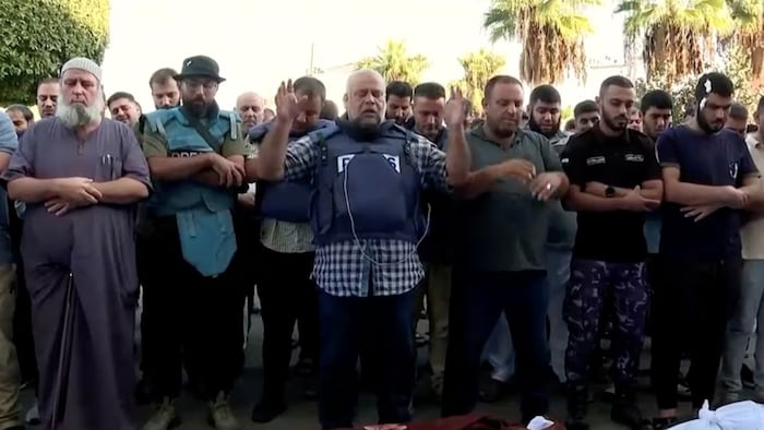 Wael Al-Dahdouh, portant une veste pare-balles identifiée «Presse», prie debout, entouré d'hommes.