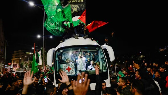 Newly released Palestinian prisoners in grey jump suits watch from inside an International Red Cross Bus surrounded by crowds outside the Israeli Ofer military prison on Nov. 26. (Ammar Awad/Reuters)