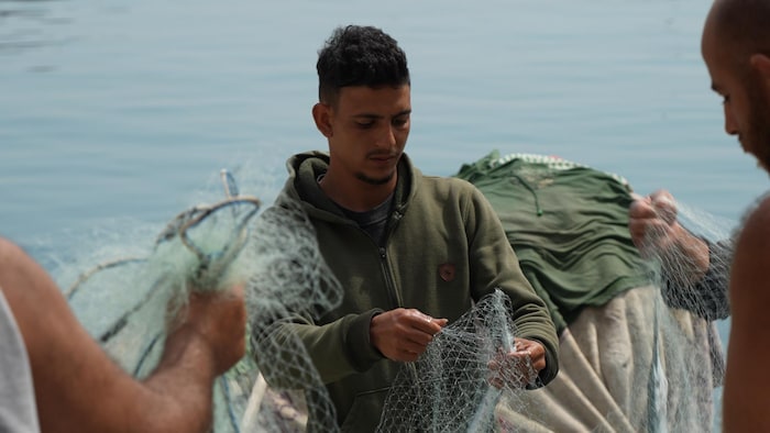 Issa Darwish removing a fish from a fishing net.