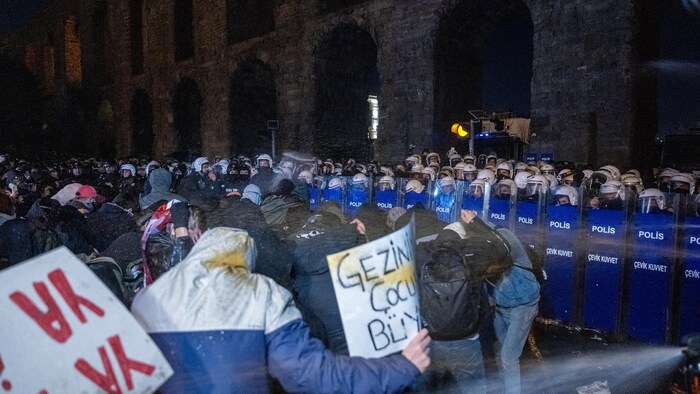 Des manifestants font face à une rangée de policiers antiémeutes.