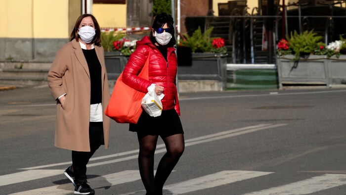 Deux femmes portant des masques traversent la rue.