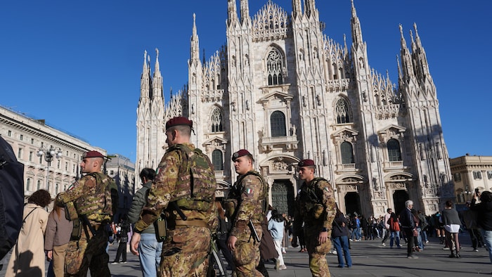 Quatre soldats autour d'un monument religieux et de visiteurs.
