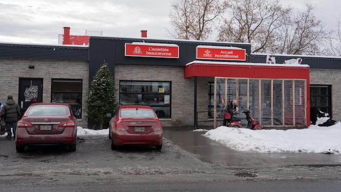 Un bâtiment en briques avec des voitures stationnées devant.