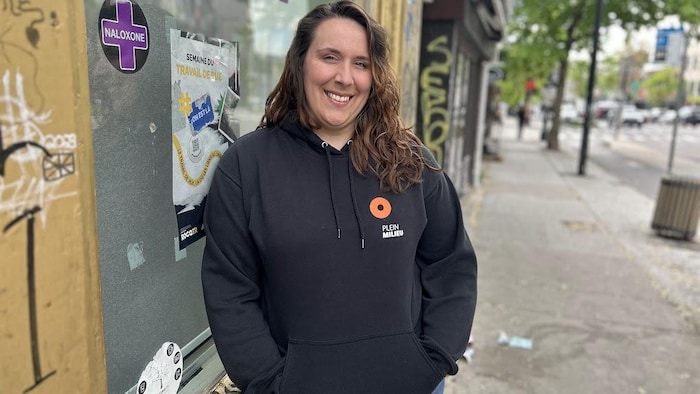 Une femme prend la pose sur une rue commerciale.