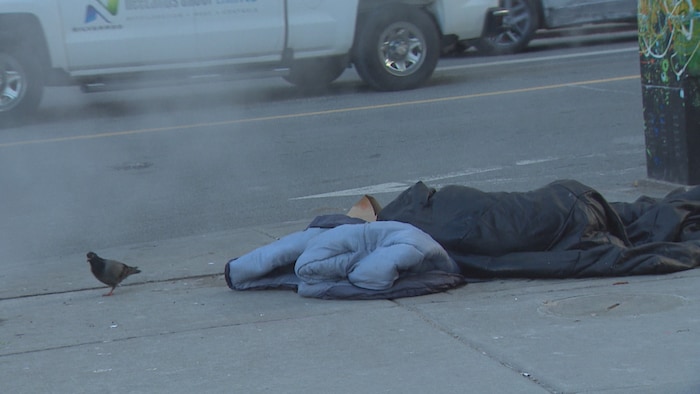 Une personne allongée sur un trottoir à Toronto.