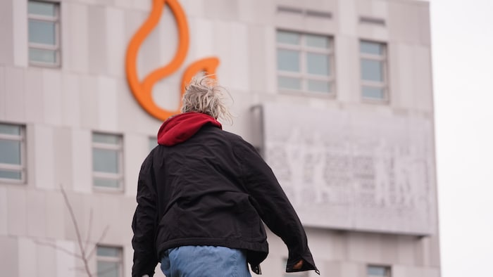 Une personne en situation d'itinérance se tient devant la façade de Lauberivière.
