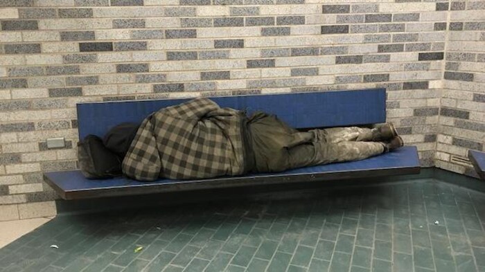 Un itinérant dormant sur un banc dans le métro Place-des-Arts à Montréal