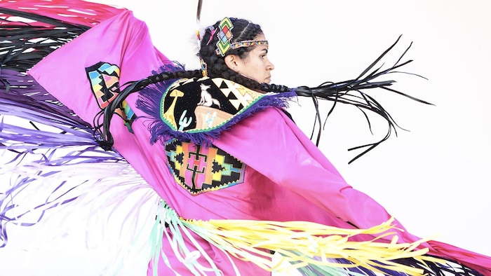 Une femme fait une danse autochtone dans un costume traditionnel.