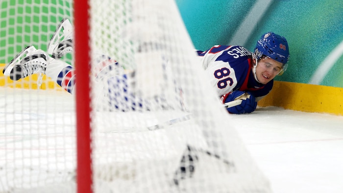 Jack Hughes est étendu sur la glace et grimace de douleur.