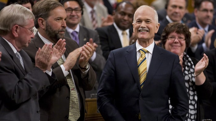 Jack Layton entouré de députés dans la Chambre des communes, dont Thomas Mulcair.