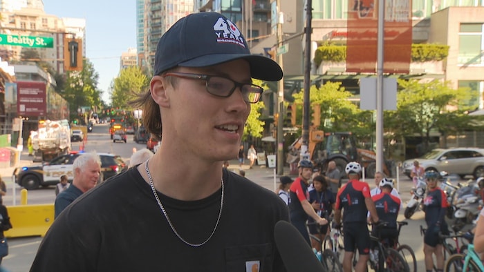 Jacob répond à des questions de journalistes, juste devant les cyclistes qui s'apprêtent à faire le Cyclotour de l'espoir.