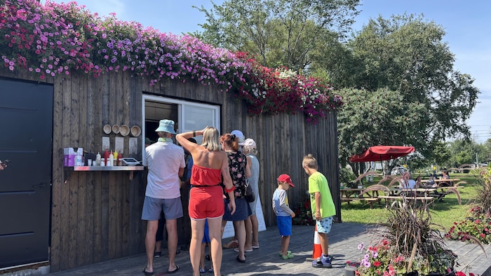 Plusieurs personnes qui font la queue devant un casse-croûte.