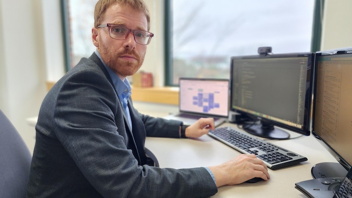 Portrait d'un homme assis devant son ordinateur.