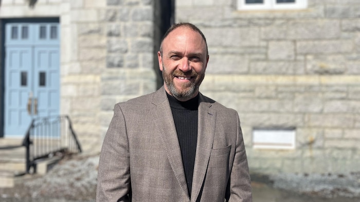 Jacques Painchaud, debout, devant des portes closes.