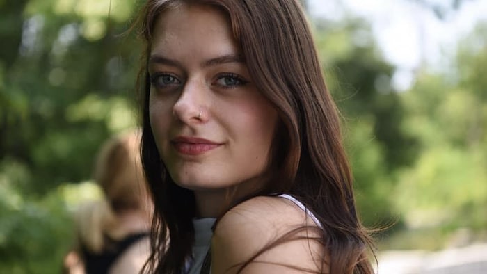 Une jeune femme aux cheveux longs sourit.