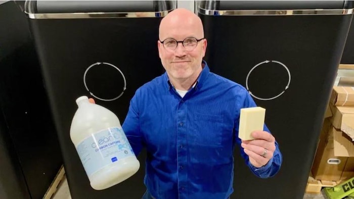 Jaeson Cardiff tient à la main du savon liquide et un pain de savon produits avec du CO2 tiré d'une technologie qu'il a développé.