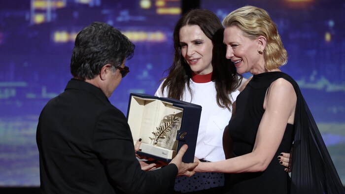 Le réalisateur, scénariste et producteur iranien Jafar Panahi célèbre avec l'actrice française et présidente du jury du 78e festival de Cannes Juliette Binoche et l'actrice et productrice australienne Cate Blanchett sur scène après avoir remporté la Palme d'Or pour le film « Un simple accident » lors de la cérémonie de clôture de la 78e édition du Festival de Cannes à Cannes.